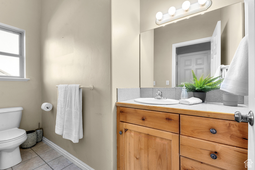 Bathroom with toilet, tile patterned flooring, vanity, and baseboards