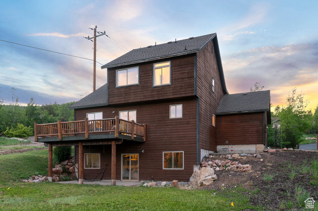 Rear view of property featuring a patio area, a yard, a deck, and roof with shingles