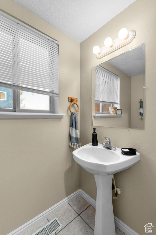 Bathroom featuring baseboards, a textured ceiling, and tile patterned flooring