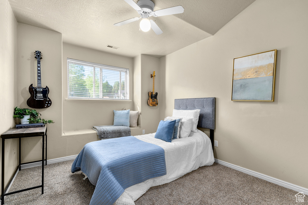 Carpeted bedroom with baseboards, ceiling fan, and a textured ceiling