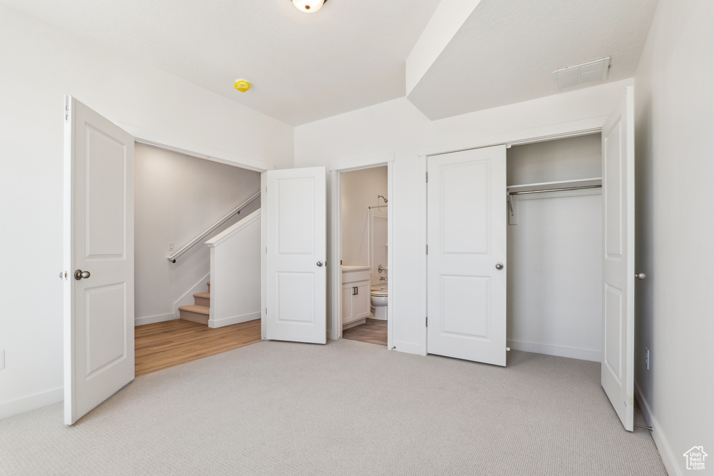 Unfurnished bedroom featuring light carpet, a closet, baseboards, and connected bathroom