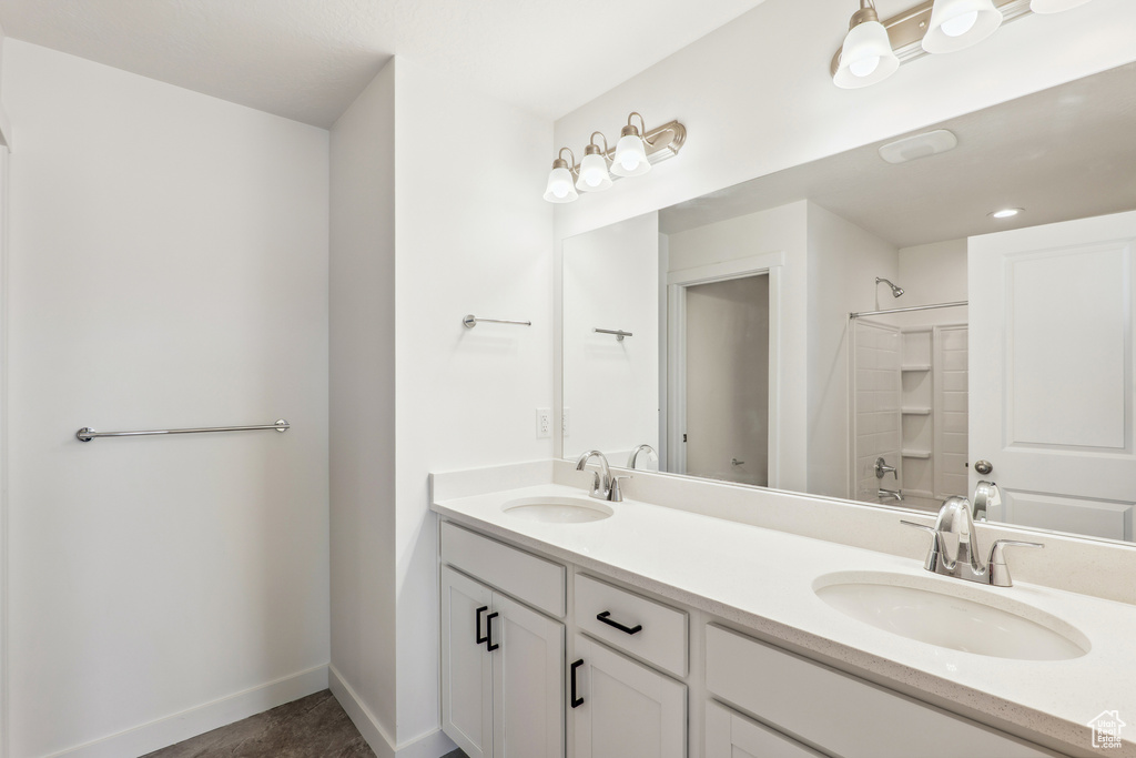Bathroom with double vanity, baseboards, and a shower