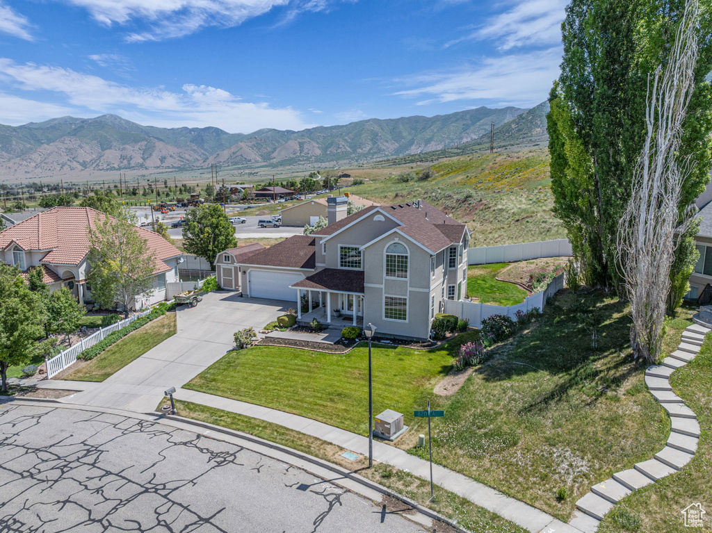 View of front of house with concrete driveway, a mountain view, and an attached garage