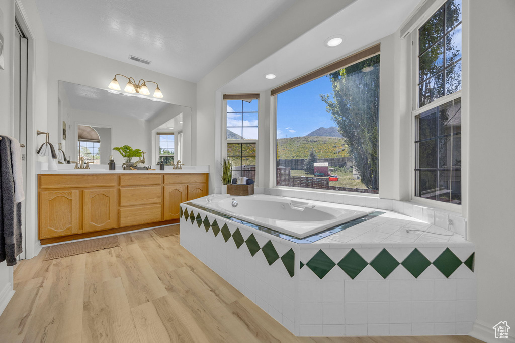 Bathroom featuring double vanity, a bath, wood finished floors, a mountain view, and a chandelier
