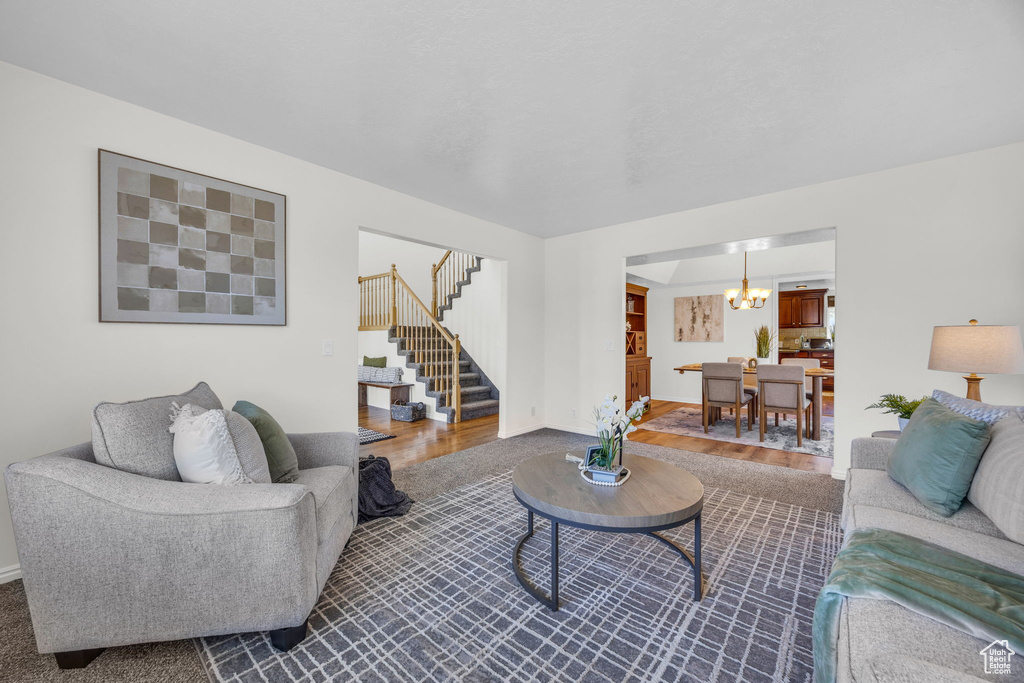 Living room featuring stairway, a chandelier, baseboards, and dark wood-style floors