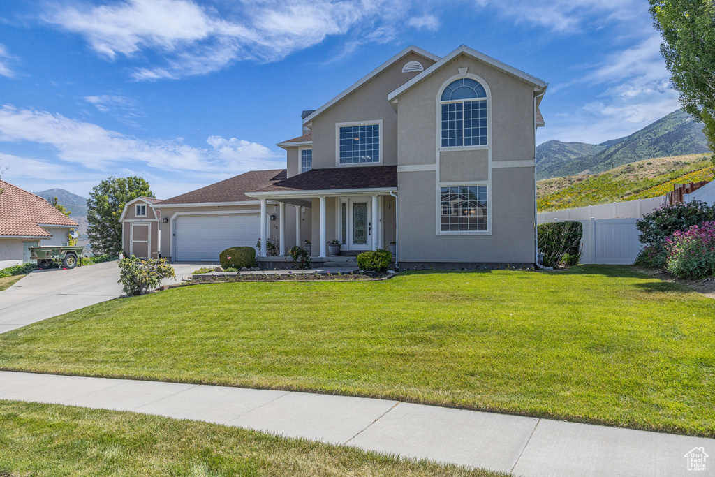 Traditional-style house with covered porch, driveway, a mountain view, and an attached garage