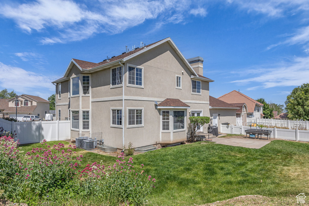 Back of property with stucco siding, a patio, a chimney, and central AC