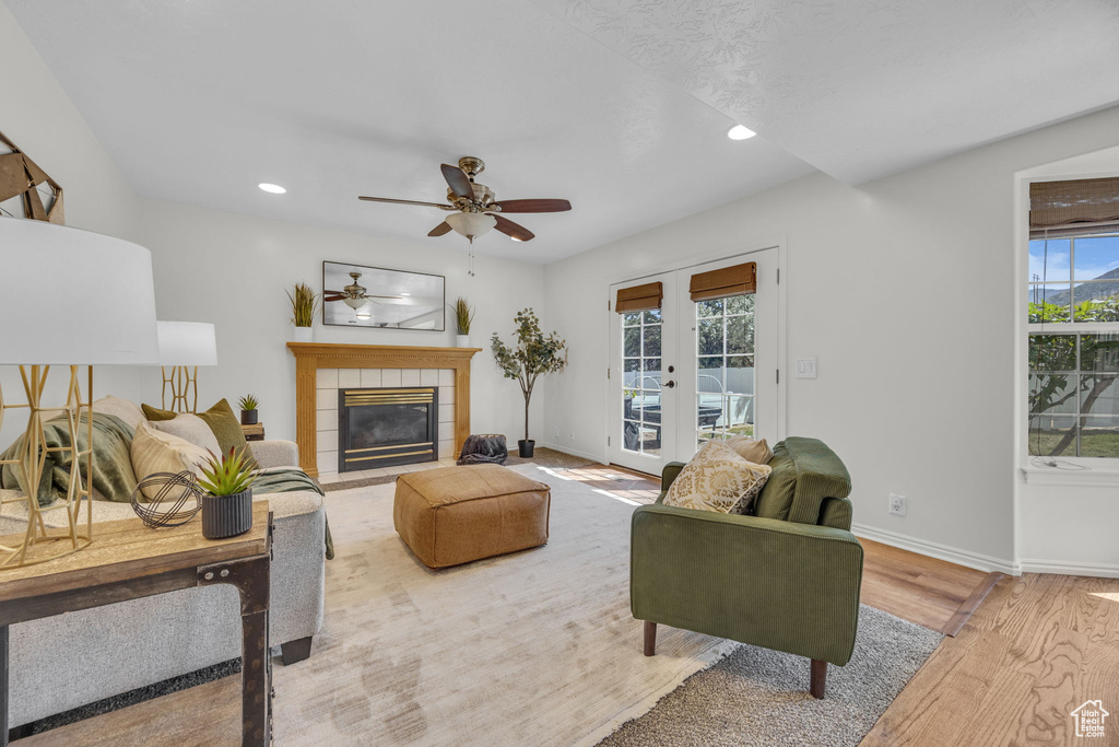 Living area with french doors, ceiling fan, wood finished floors, recessed lighting, and a tile fireplace