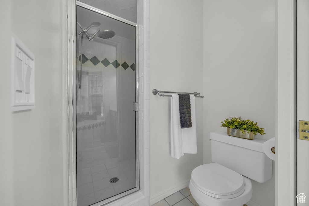 Bathroom featuring toilet, a stall shower, tile patterned flooring, and baseboards