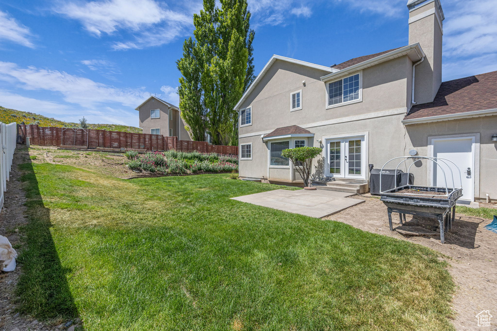 Back of property featuring french doors, a patio area, central AC unit, a chimney, and roof with shingles