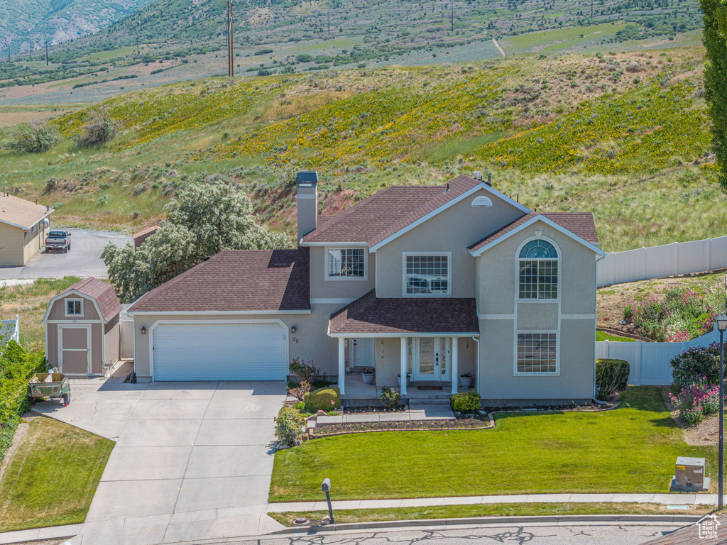 Traditional-style home featuring a garage, concrete driveway, stucco siding, a chimney, and covered porch