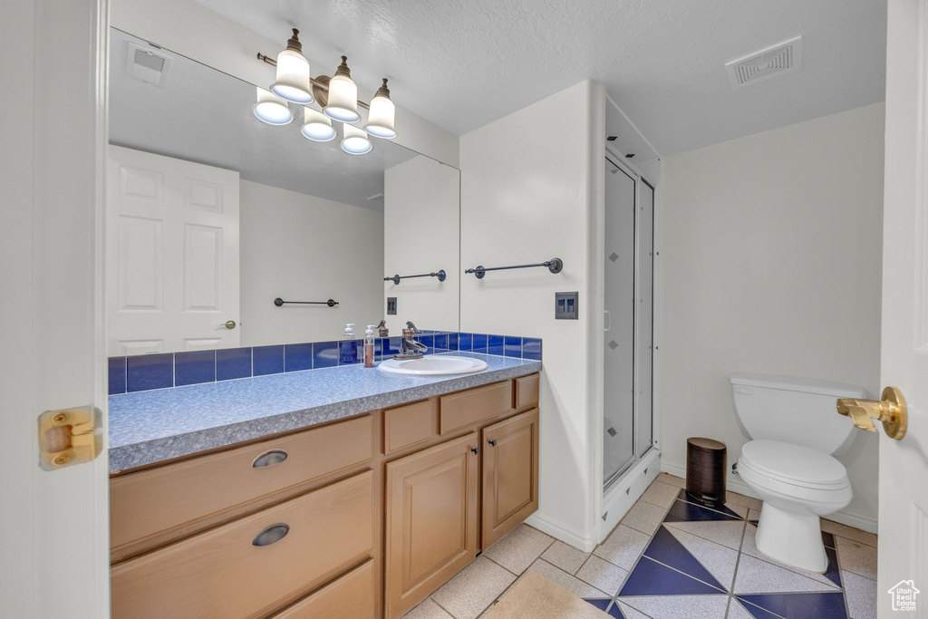 Bathroom featuring vanity, toilet, a shower stall, and tile patterned floors