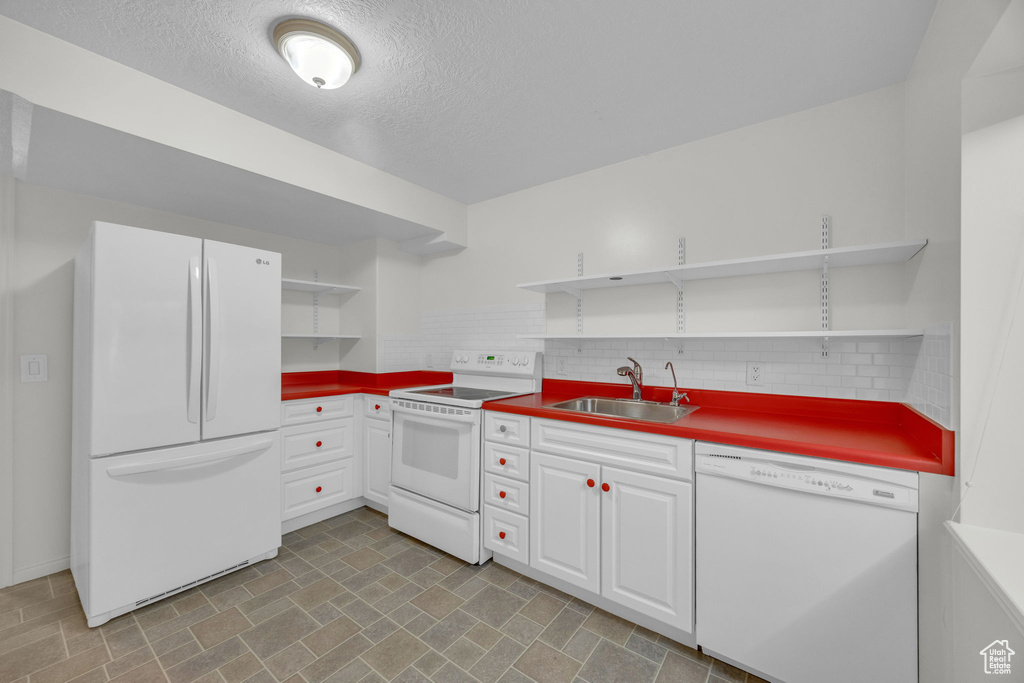 Kitchen with open shelves, white appliances, a sink, white cabinetry, and a textured ceiling