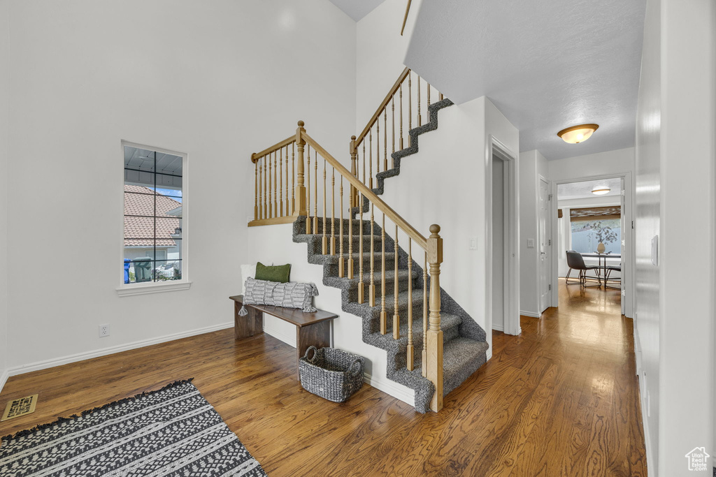 Stairs featuring wood finished floors, baseboards, and a towering ceiling