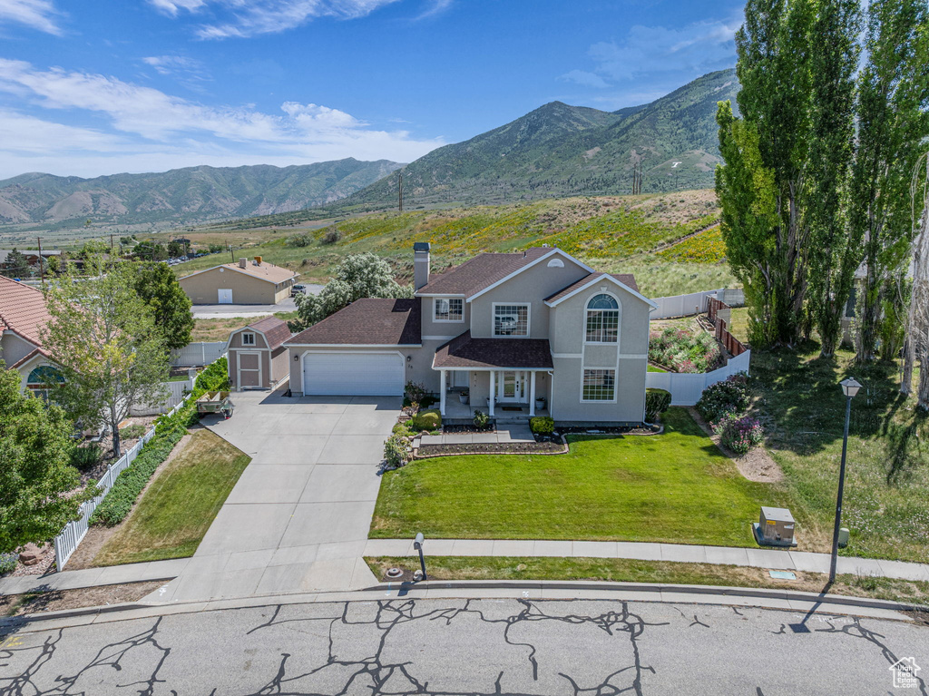 Traditional home featuring concrete driveway, a mountain view, an attached garage, stucco siding, and a chimney