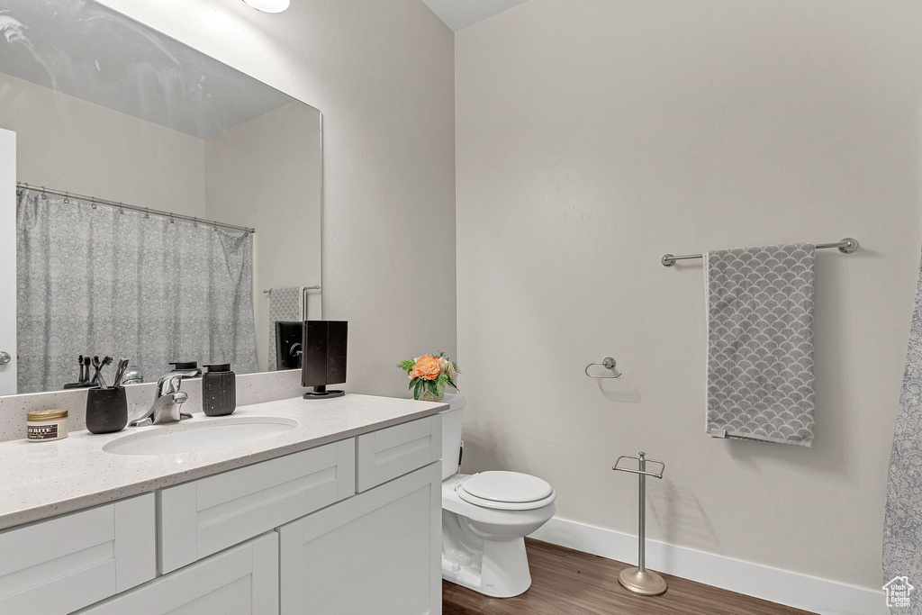 Bathroom featuring wood finished floors, vanity, toilet, and baseboards