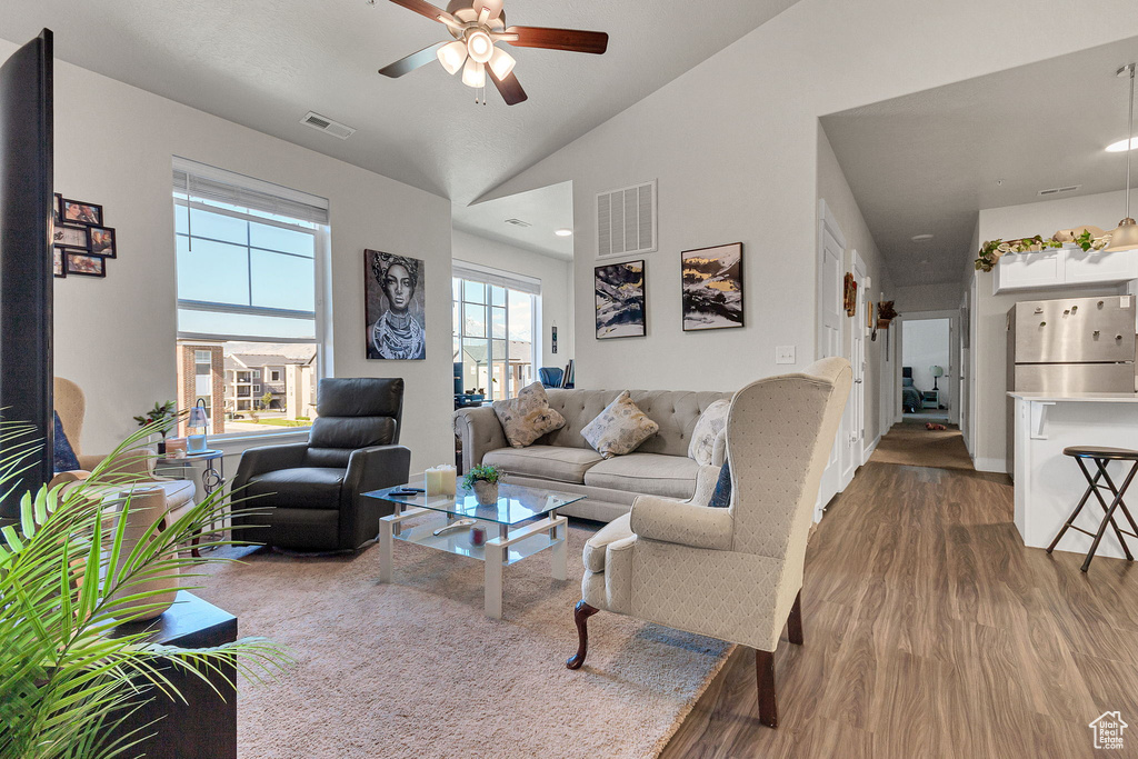Living room with wood finished floors, ceiling fan, and lofted ceiling