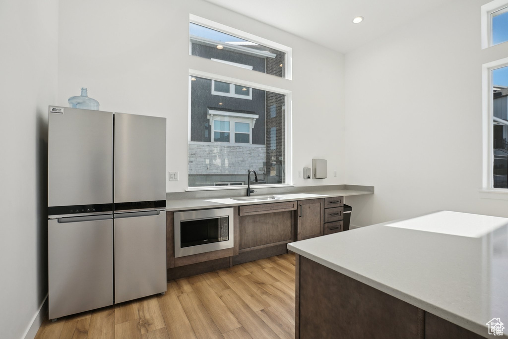 Kitchen with stainless steel appliances, a sink, light wood-style flooring, light countertops, and recessed lighting