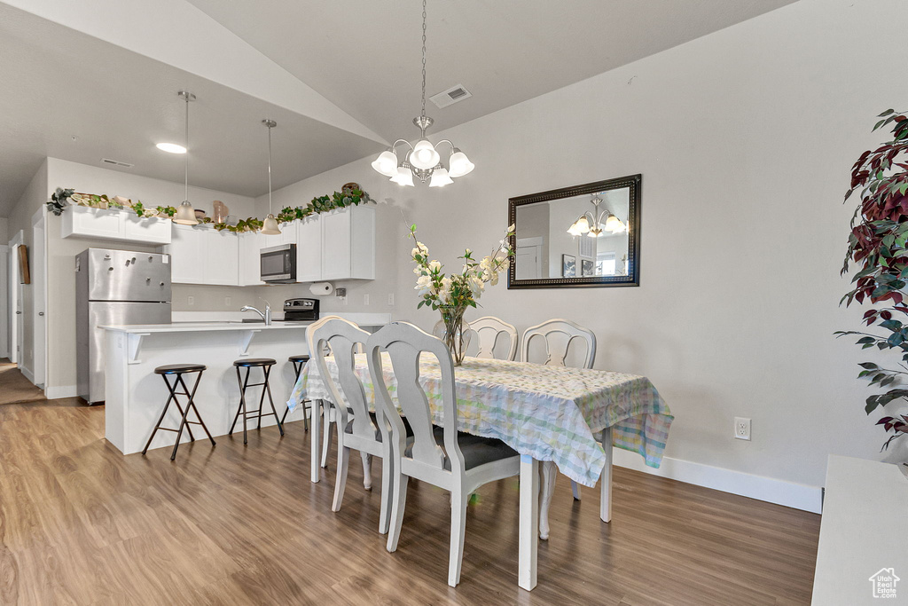 Dining room featuring a chandelier, light wood finished floors, baseboards, and high vaulted ceiling