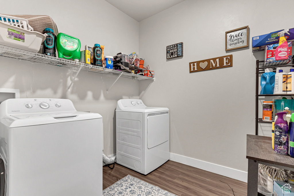 Laundry area with washing machine and clothes dryer, wood finished floors, and baseboards