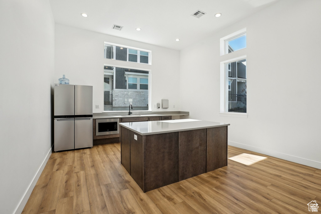 Kitchen with stainless steel appliances, a sink, light countertops, light wood-style floors, and baseboards