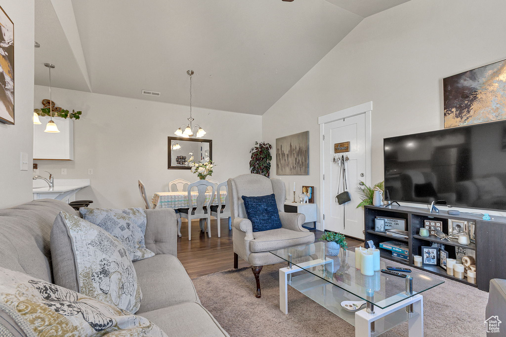 Carpeted living room with a chandelier, a sink, and high vaulted ceiling