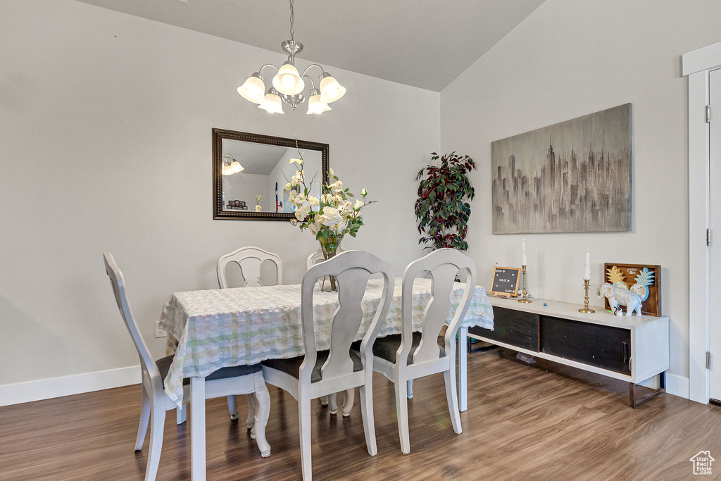 Dining space featuring a chandelier, lofted ceiling, wood finished floors, and baseboards