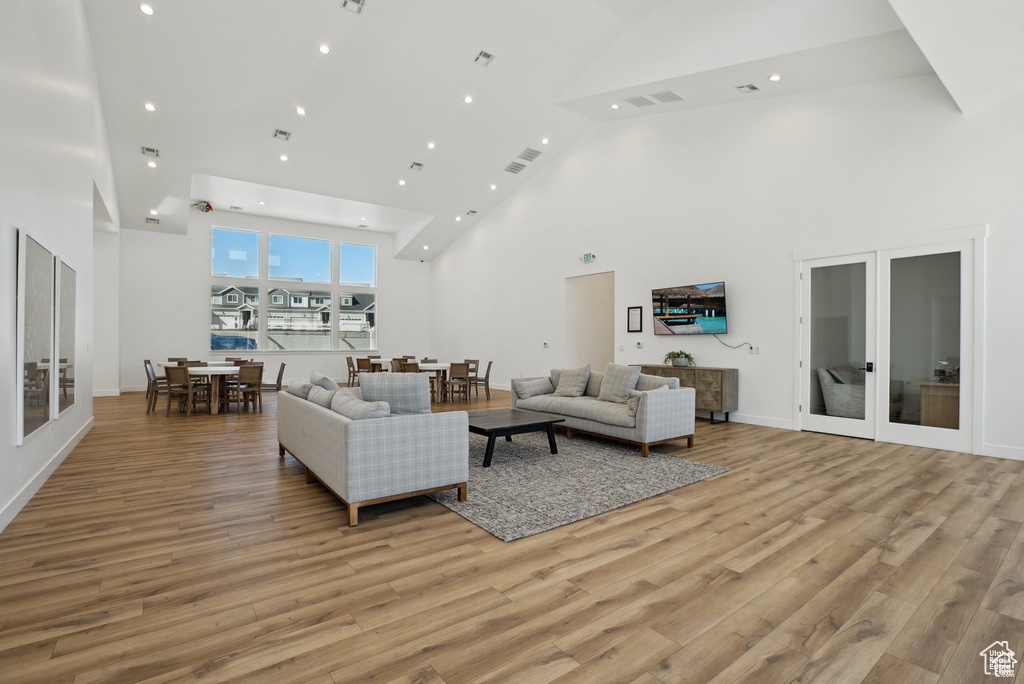 Living area featuring high vaulted ceiling, light wood finished floors, french doors, recessed lighting, and baseboards