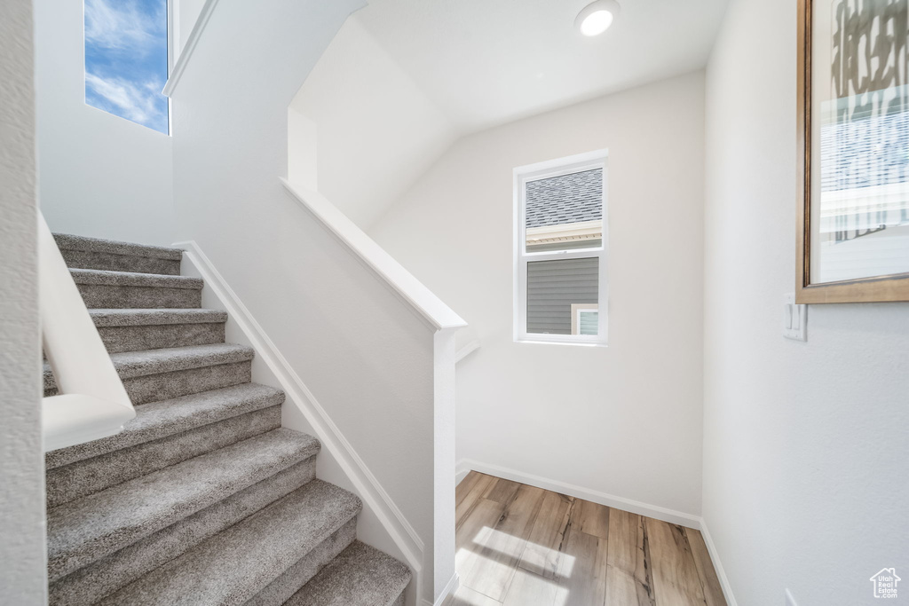 Stairway featuring wood finished floors and recessed lighting