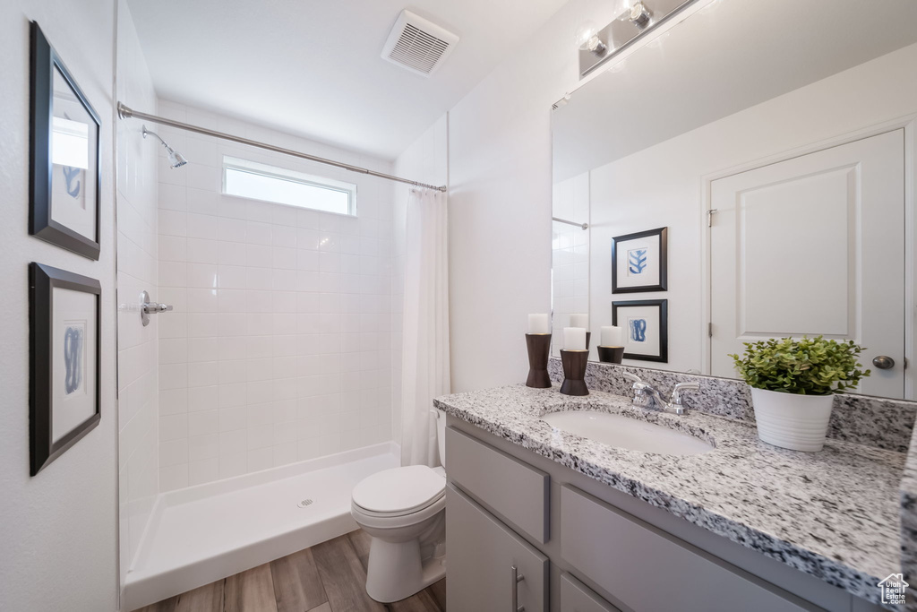 Full bathroom featuring vanity, wood finished floors, and a tile shower