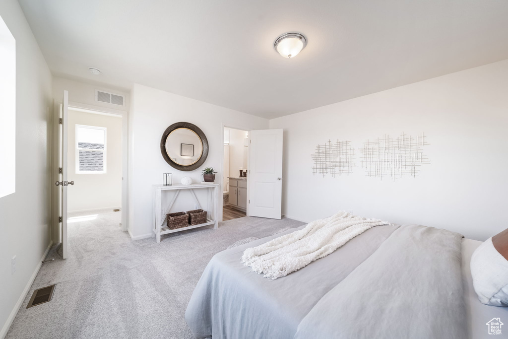 Bedroom with light carpet and connected bathroom