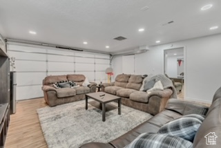 Living area featuring light wood finished floors, recessed lighting, and a garage