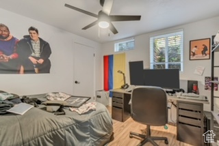 Bedroom with wood finished floors, an office area, and a ceiling fan