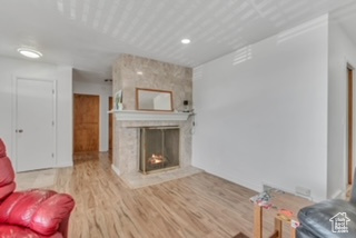 Living room with wood finished floors, a fireplace, and recessed lighting