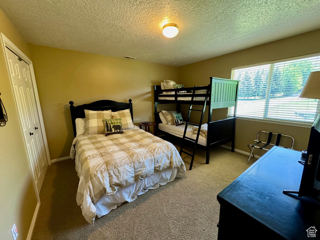 Bedroom with carpet floors, a textured ceiling, and a closet
