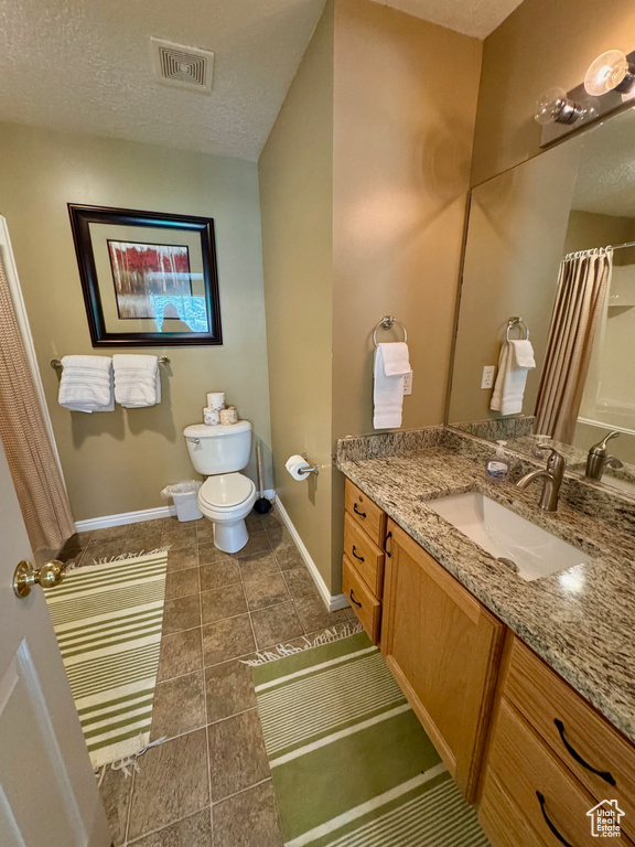 Full bath featuring vanity, a textured ceiling, tile patterned flooring, and a shower with shower curtain