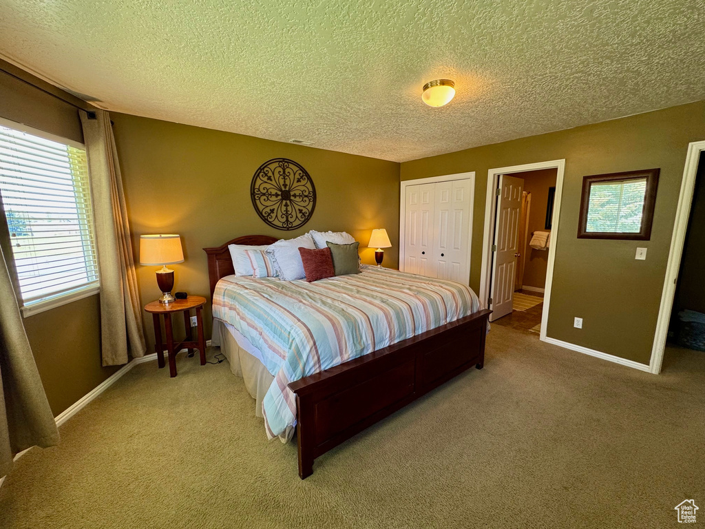Carpeted bedroom featuring a textured ceiling and a closet