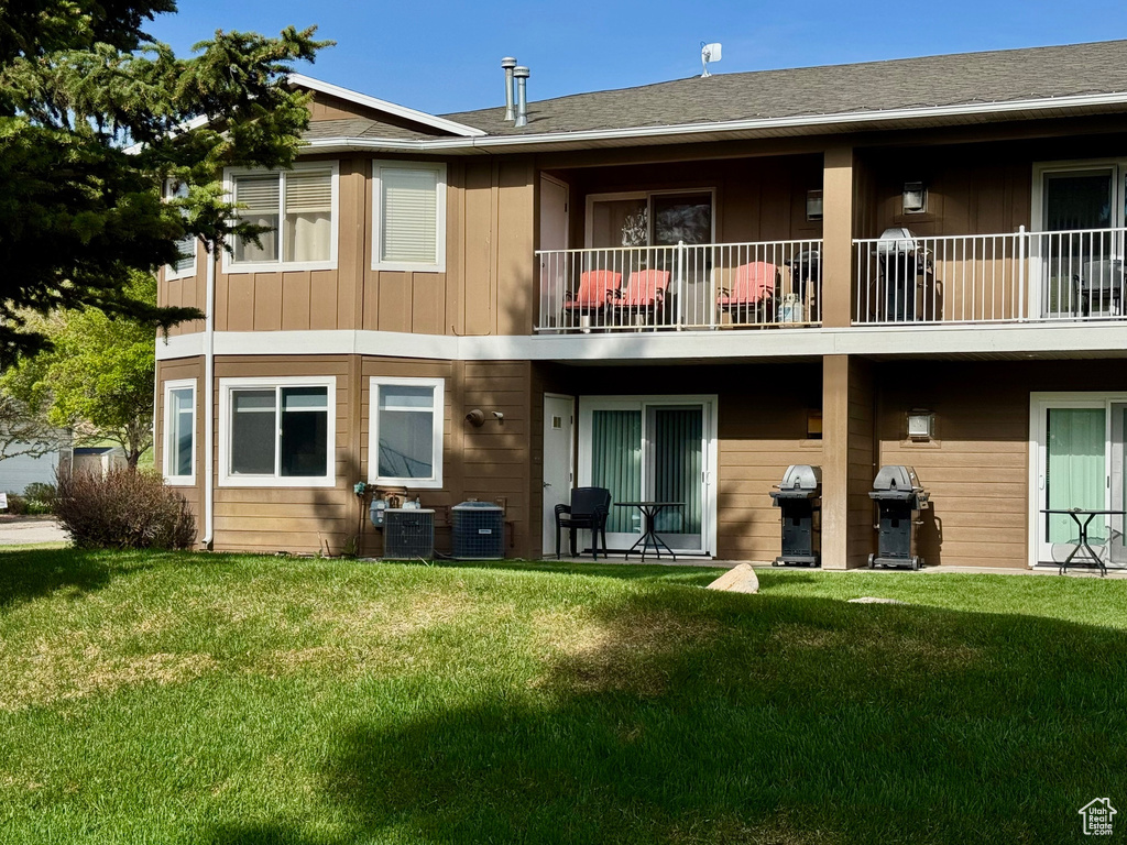 Rear view of property featuring a balcony, a yard, and board and batten siding