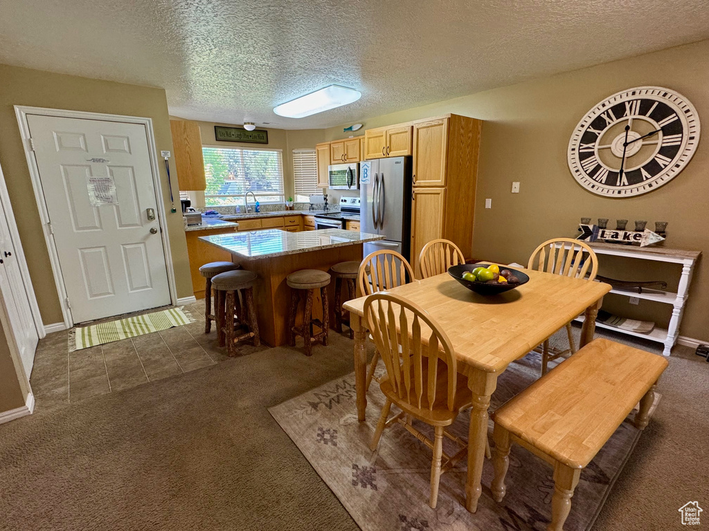 Dining space with dark colored carpet, a textured ceiling, and dark tile patterned floors
