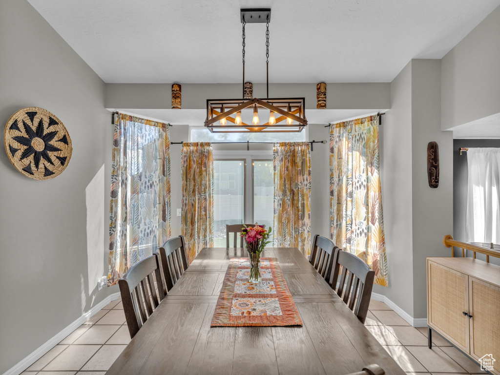 Dining space with light tile patterned flooring, baseboards, and a chandelier