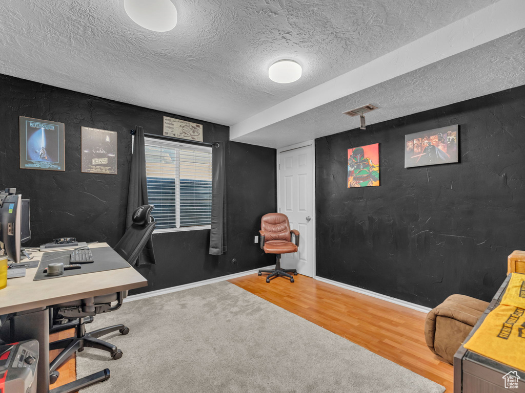 Home office with wood finished floors, baseboards, and a textured ceiling