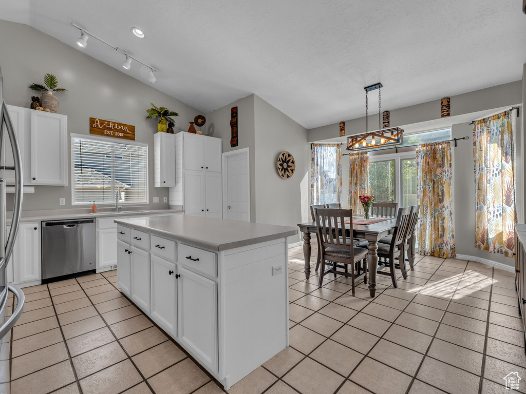 Kitchen with stainless steel dishwasher, light tile patterned floors, light countertops, a chandelier, and white cabinetry