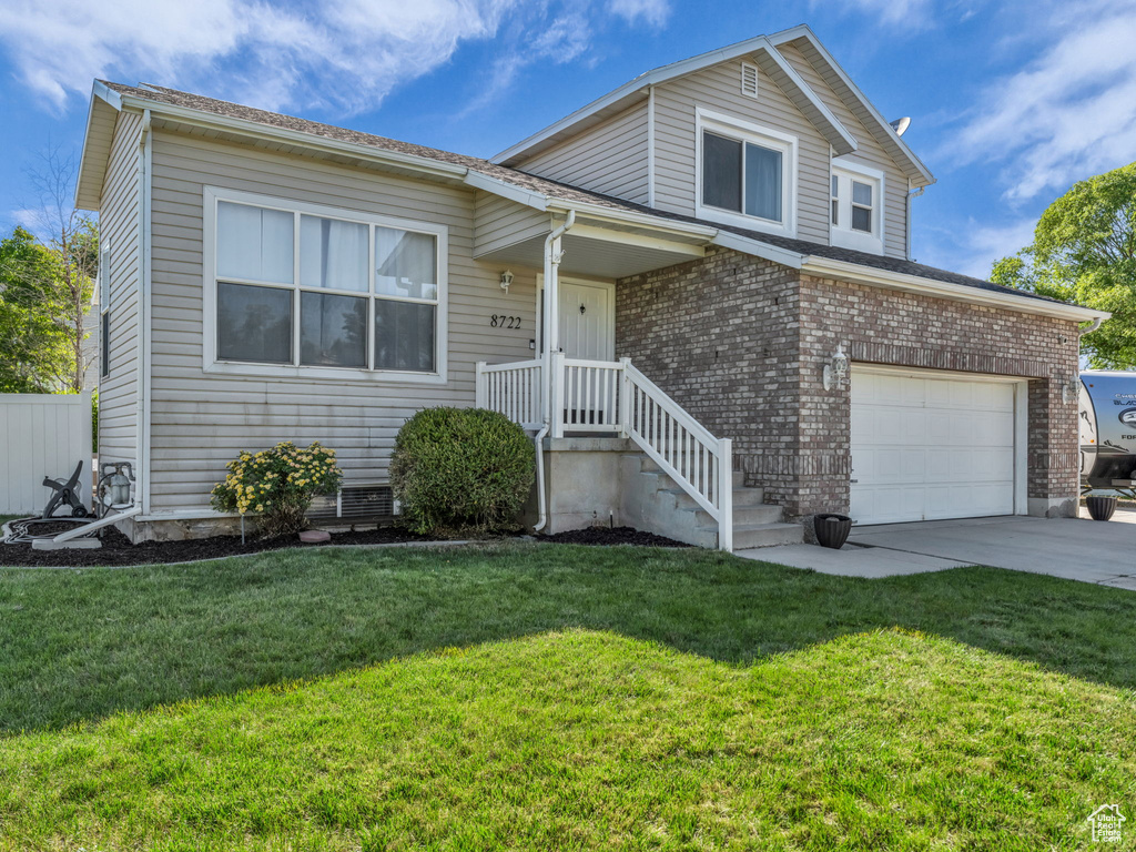 View of front of home featuring concrete driveway, a front lawn, and a garage