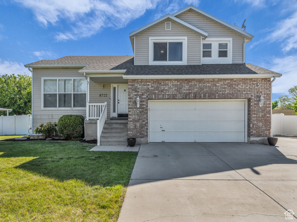 Traditional-style house with a garage, brick siding, concrete driveway, and roof with shingles