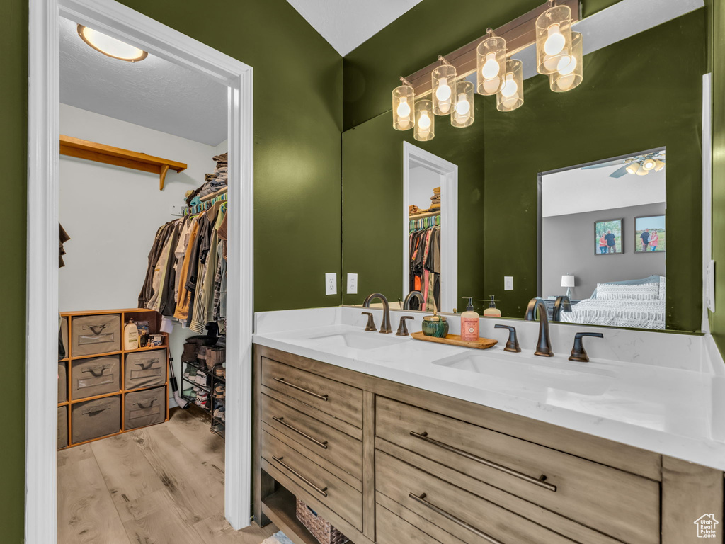 Full bathroom with double vanity, a walk in closet, wood finished floors, and ensuite bath