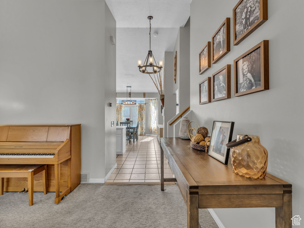 Hall with a chandelier, carpet floors, baseboards, and tile patterned floors