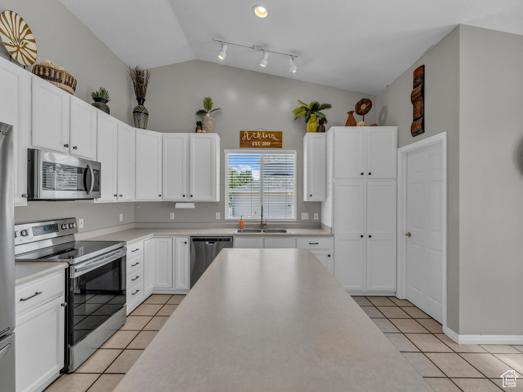 Kitchen featuring appliances with stainless steel finishes, light tile patterned floors, a sink, light countertops, and white cabinets