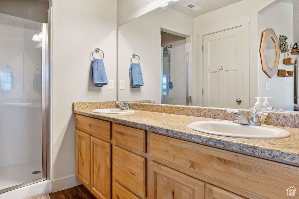 Bathroom with a stall shower, double vanity, and wood finished floors