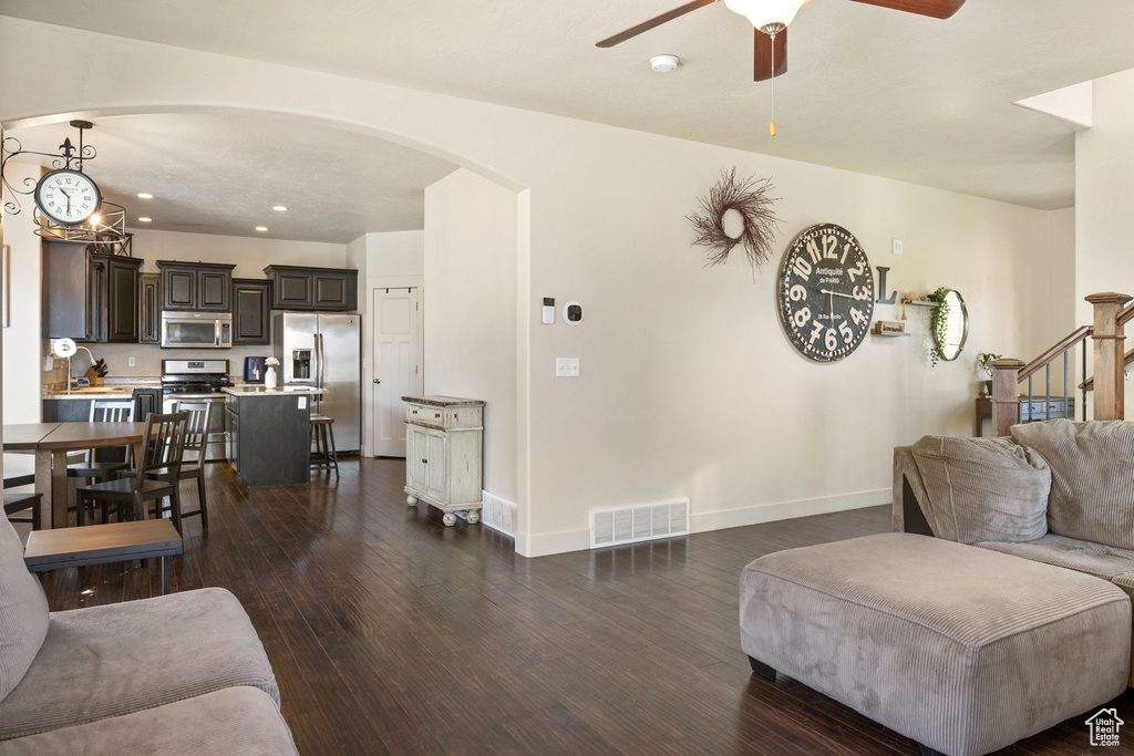 Living room featuring arched walkways, a ceiling fan, baseboards, dark wood-style flooring, and recessed lighting