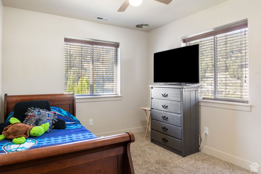 Bedroom with light colored carpet, baseboards, and a ceiling fan